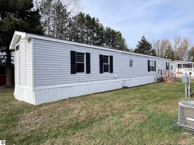 manufactured / mobile home with a front yard, cooling unit, and a deck