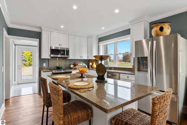 kitchen featuring appliances with stainless steel finishes, white cabinets, a kitchen bar, and a wealth of natural light