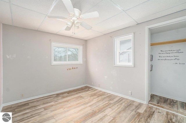 1219 Elm St, Frankfort, MI 49635 - unfurnished bedroom featuring a ceiling fan, a closet, light wood-style floors, a drop ceiling, and baseboards