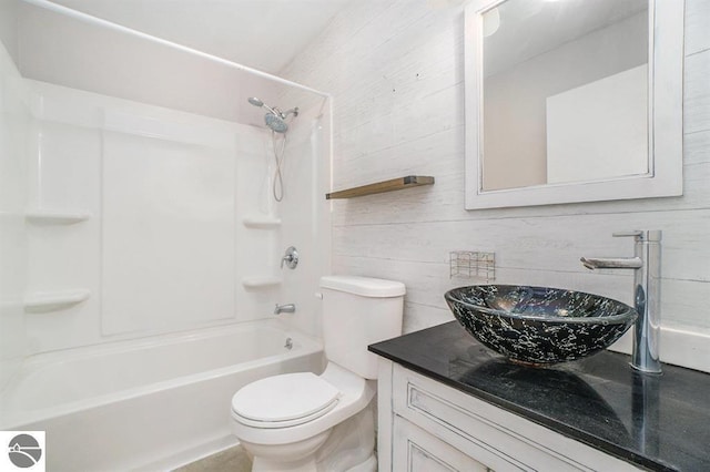 1219 Elm St, Frankfort, MI 49635 - bathroom with wooden walls, vanity, tub / shower combination, and toilet