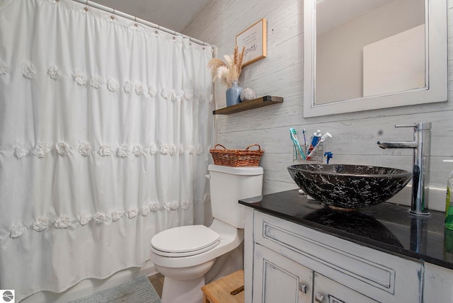 full bathroom with toilet, wooden walls, vanity, and shower / bath combo