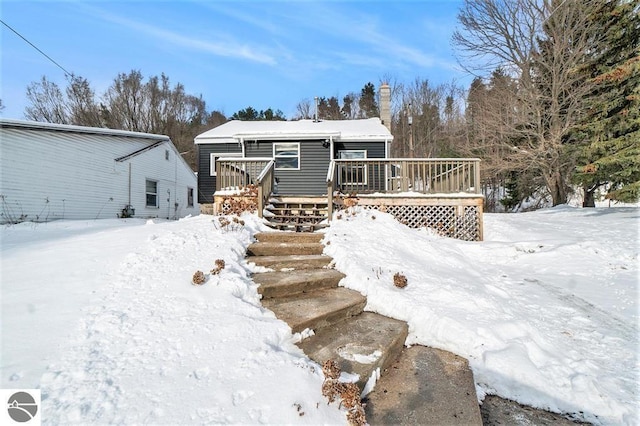 1219 Elm St, Frankfort, MI 49635 - snow covered property featuring a chimney, stairway, and a deck