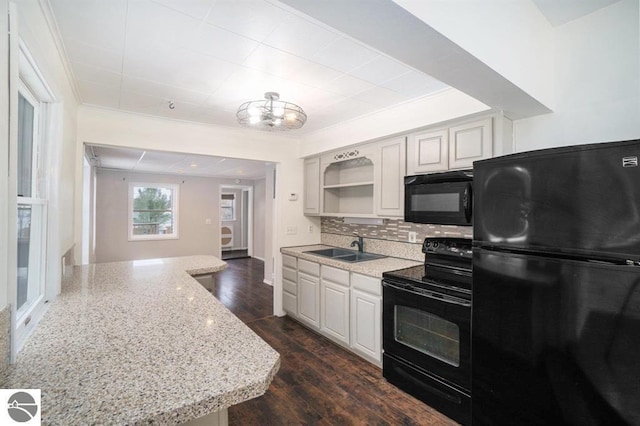 1219 Elm St, Frankfort, MI 49635 - kitchen featuring light stone counters, tasteful backsplash, a sink, black appliances, and dark wood-style floors