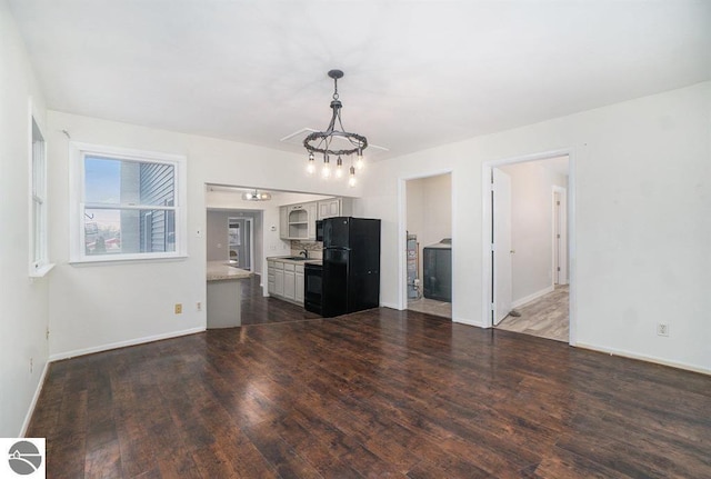 1219 Elm St, Frankfort, MI 49635 - unfurnished living room with baseboards, dark wood-style flooring, a chandelier, and a sink