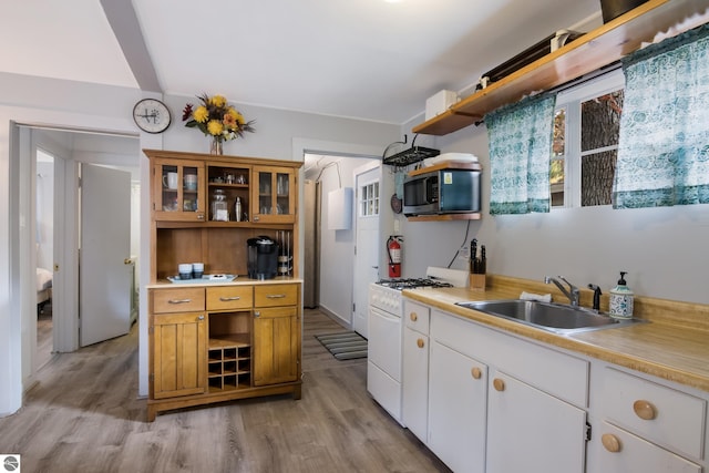 kitchen featuring stainless steel microwave, open shelves, a sink, and gas range gas stove