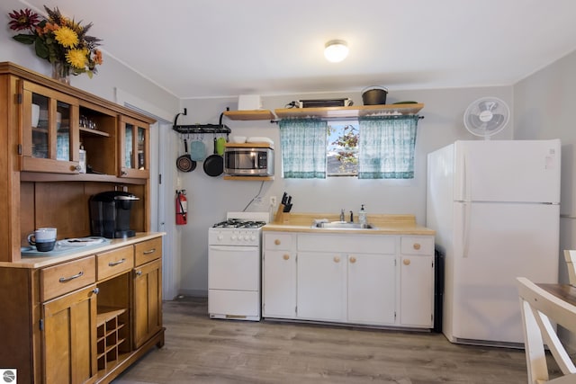 kitchen featuring a sink, light countertops, open shelves, and white appliances