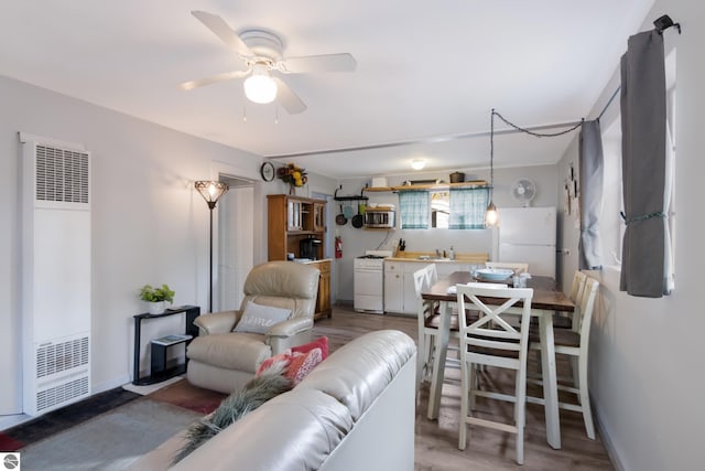 living room featuring light wood-type flooring, a heating unit, and a ceiling fan