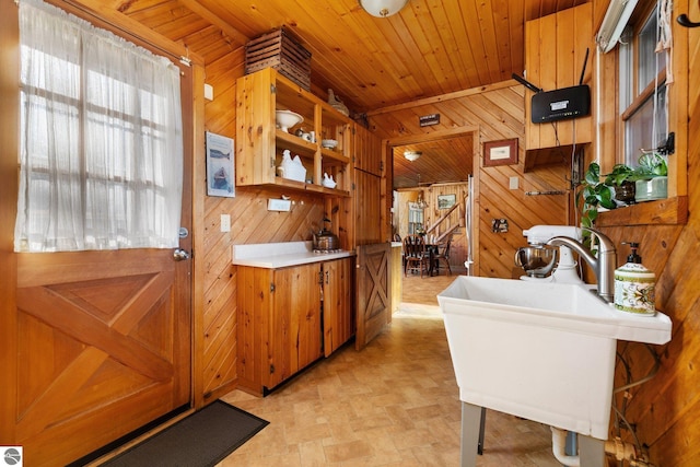 kitchen featuring sink, a breakfast bar, wooden ceiling, and wood walls