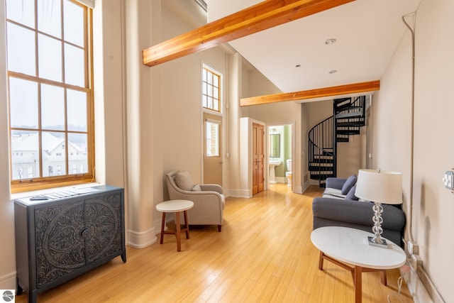 sitting room with wood finished floors, baseboards, high vaulted ceiling, and stairs