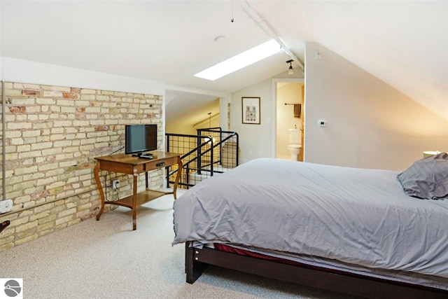 carpeted bedroom featuring lofted ceiling with skylight and brick wall