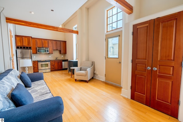 living room featuring baseboards, light wood-type flooring, and a high ceiling