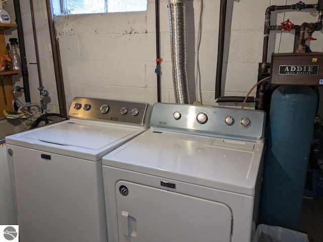 clothes washing area featuring concrete block wall and separate washer and dryer
