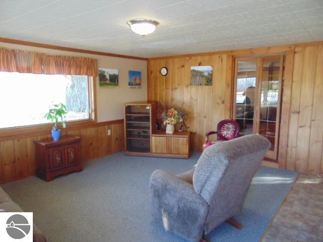 carpeted living room with ornamental molding and wooden walls