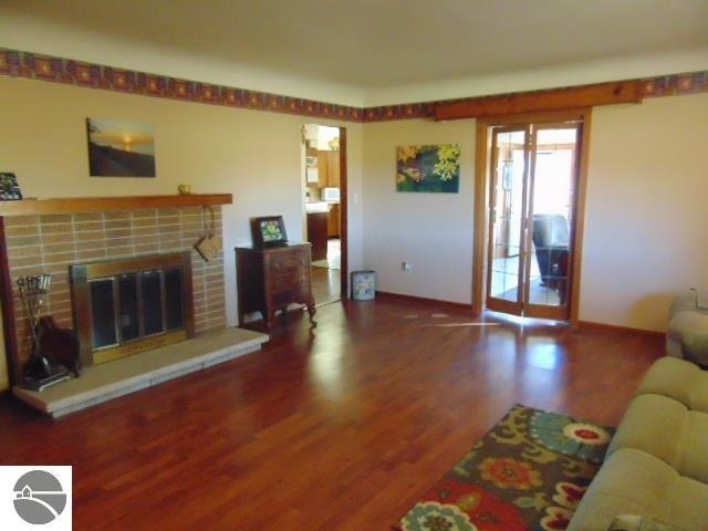 living room featuring a brick fireplace and dark hardwood / wood-style flooring