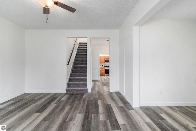 interior space with a ceiling fan, a textured ceiling, stairs, and dark wood finished floors