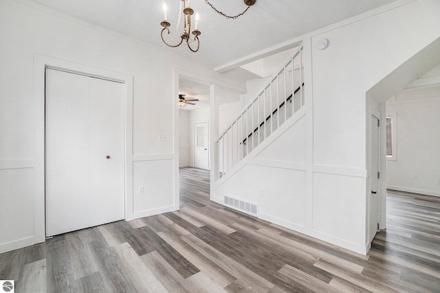 foyer with a textured ceiling, wood-type flooring, and ceiling fan with notable chandelier