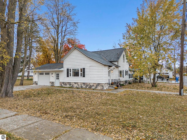 view of side of property featuring a lawn, roof with shingles, driveway, and a garage