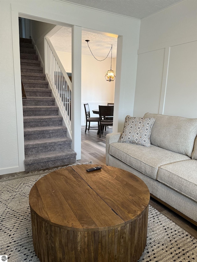 living room featuring wood finished floors, a notable chandelier, and stairway