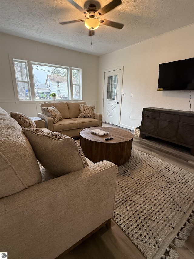 living area with wood finished floors, a textured ceiling, and a ceiling fan