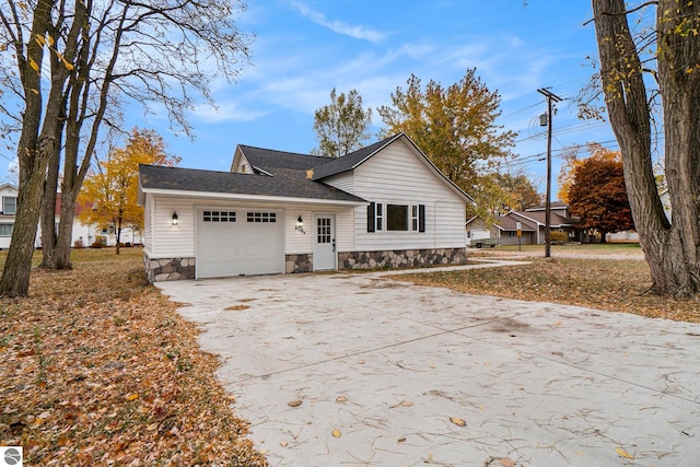 view of front of home featuring stone siding, a shingled roof, driveway, and a garage