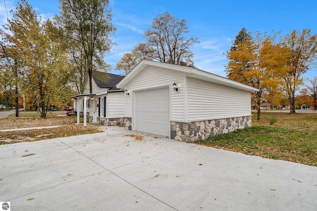view of home's exterior featuring an attached garage, driveway, and stone siding