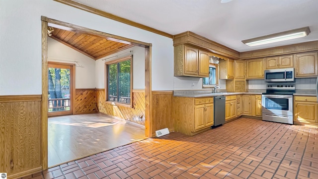 kitchen with wood walls, stainless steel appliances, crown molding, vaulted ceiling, and tasteful backsplash