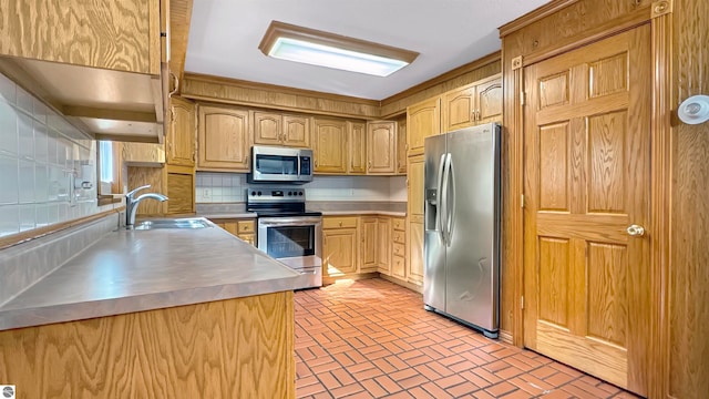 kitchen with decorative backsplash, stainless steel counters, sink, light brown cabinetry, and appliances with stainless steel finishes