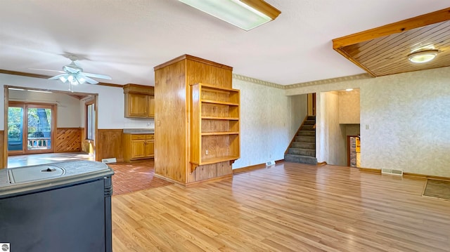 kitchen with light hardwood / wood-style flooring, wood walls, crown molding, and ceiling fan