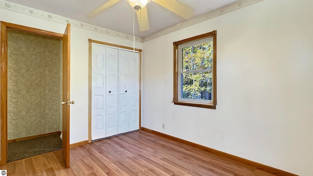 unfurnished bedroom featuring a closet, wood-type flooring, and ceiling fan