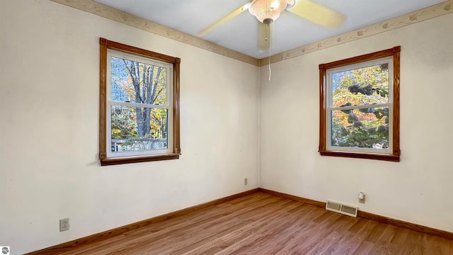 unfurnished room with a wealth of natural light, wood-type flooring, and ceiling fan