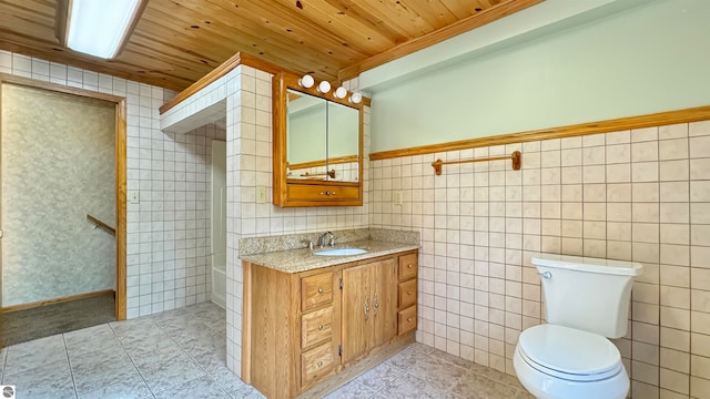 bathroom with toilet, vanity, and tile walls