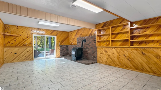 unfurnished living room with wood walls, a wood stove, and built in features