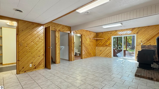 unfurnished living room featuring wooden walls and a wood stove