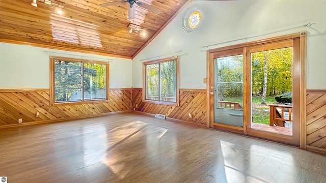 interior space with wooden walls, wooden ceiling, hardwood / wood-style floors, high vaulted ceiling, and ceiling fan