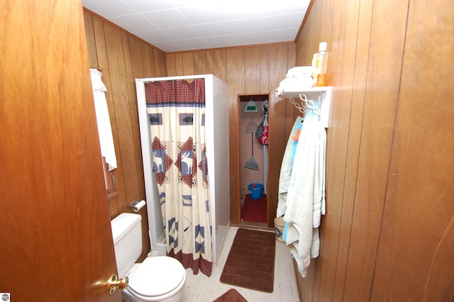 bathroom featuring toilet, wood walls, and a shower with curtain