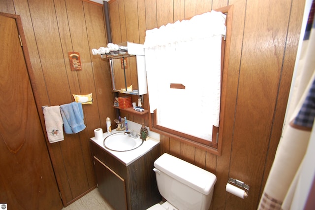 bathroom with vanity, toilet, and wood walls