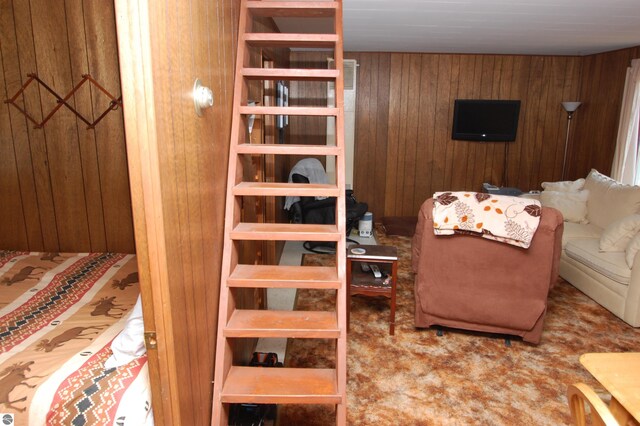 carpeted living room featuring wooden walls