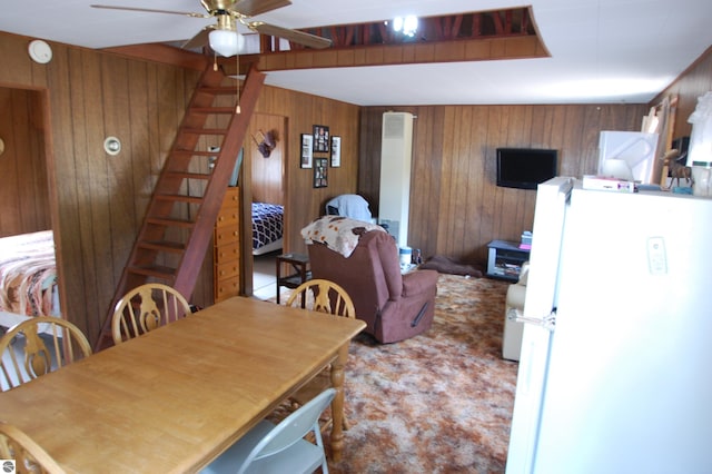 dining area featuring wooden walls and ceiling fan