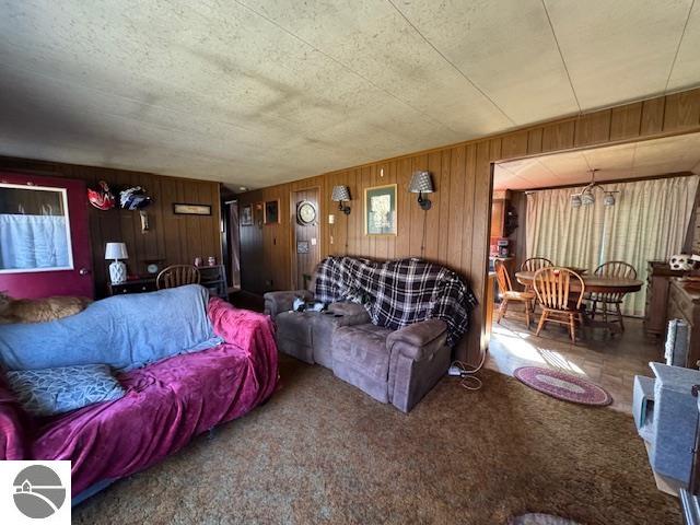 carpeted living room with wood walls and a textured ceiling