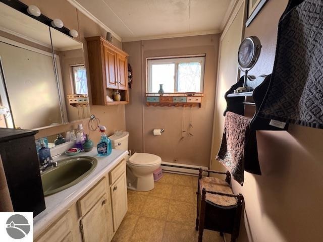 bathroom with baseboard heating, vanity, ornamental molding, and toilet