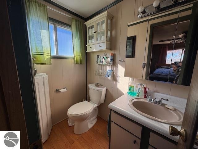 bathroom with toilet, ceiling fan, vanity, hardwood / wood-style flooring, and washer and clothes dryer