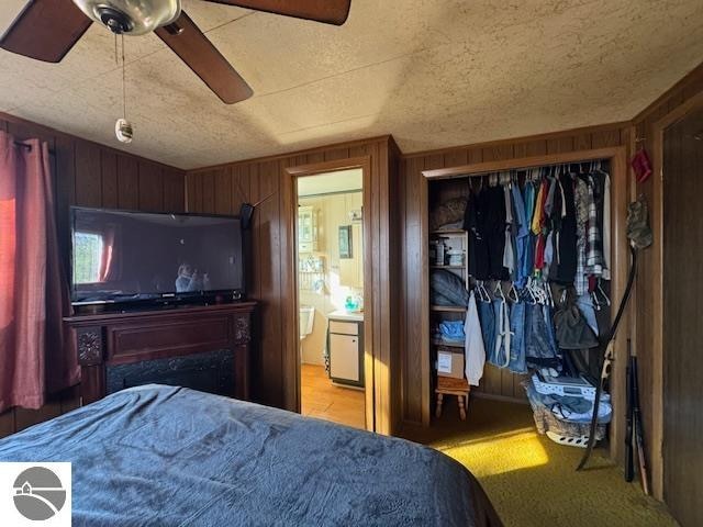 bedroom featuring light carpet, a closet, wooden walls, and ceiling fan