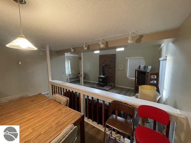 kitchen featuring a textured ceiling, a wood stove, dark hardwood / wood-style flooring, and track lighting