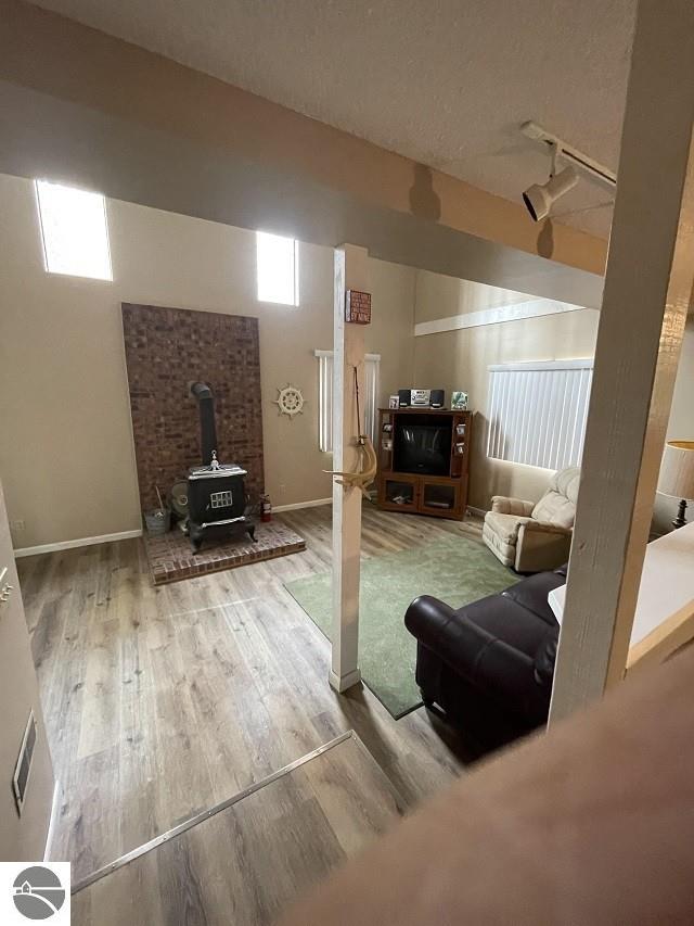 basement with a wood stove, track lighting, and wood-type flooring