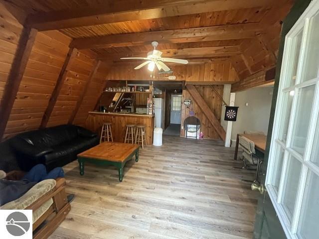 interior space with a barn door, lofted ceiling with beams, hardwood / wood-style floors, ceiling fan, and wooden ceiling