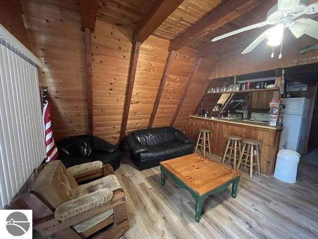 living room featuring beam ceiling, wood-type flooring, wooden ceiling, and indoor bar