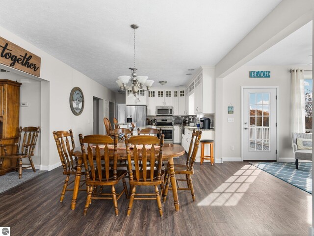 dining area with sink, a chandelier, a textured ceiling, and dark hardwood / wood-style flooring