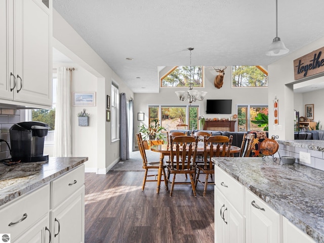 kitchen with dark wood-type flooring, white cabinets, light stone counters, and decorative light fixtures