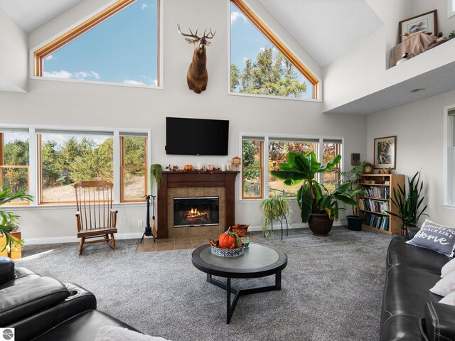 carpeted living room featuring high vaulted ceiling and a tile fireplace