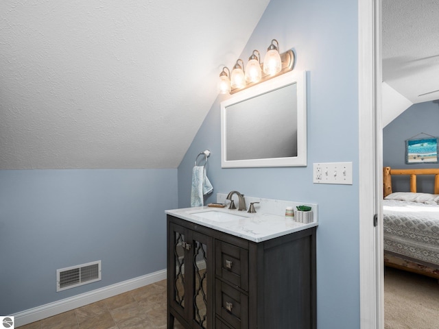 bathroom featuring vanity, vaulted ceiling, and a textured ceiling